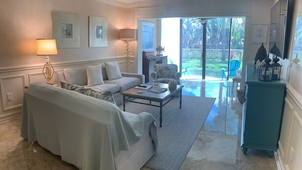 Un salón con sofá, mesa de centro y vistas al exterior.