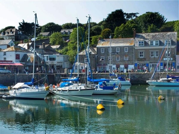 A harbor with boats docked, buildings in the background, and a clear sky.