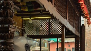 Zona de bar amb barra de fusta, separador de latici i sòl de rajola.