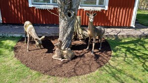 Un bâtiment rouge avec le chiffre « 12 » sur la fenêtre, entouré d’un arbre et de trois statues de cerfs.