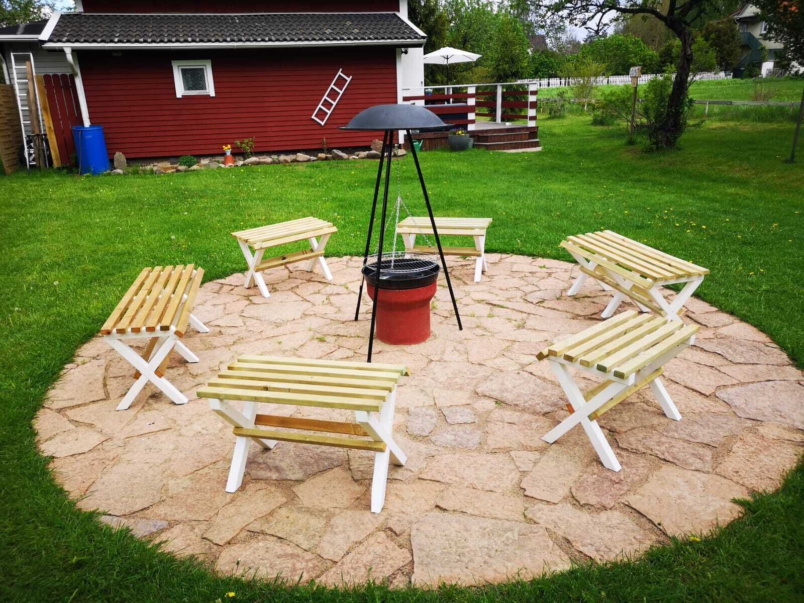 Un espace extérieur circulaire aménagé avec six fauteuils de jardin en bois et un barbecue central.