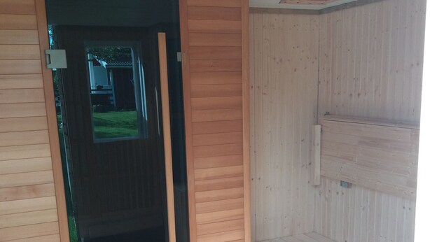 Une pièce aux murs en bois et dont la porte donne sur un espace extérieur.