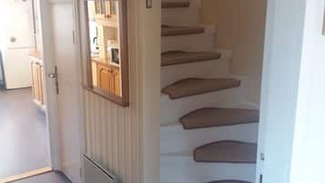 Een trap met een houten afwerking en een witte deur met een klein raam.
