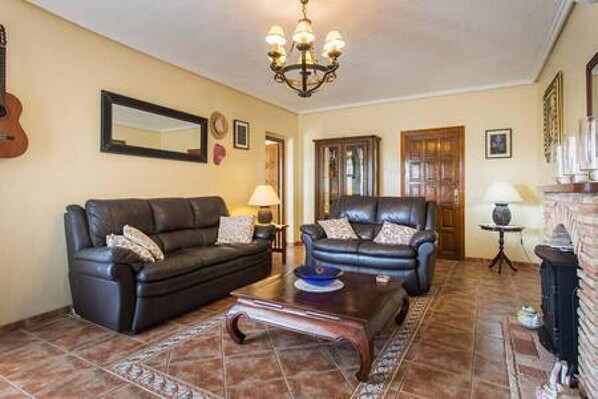 Ein Wohnzimmer mit einer schwarzen Ledersofa, einem passenden Sessel, einem Couchtisch und einer Deckenleuchte.