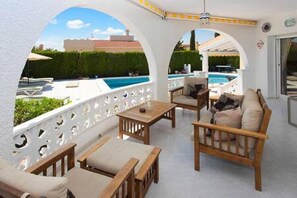 Eine Terrasse im Freien mit Holzmöbeln und Blick auf einen Swimmingpool.
