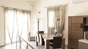 A modern dining area with a wooden table and chairs, a floor lamp, and a built-in oven.