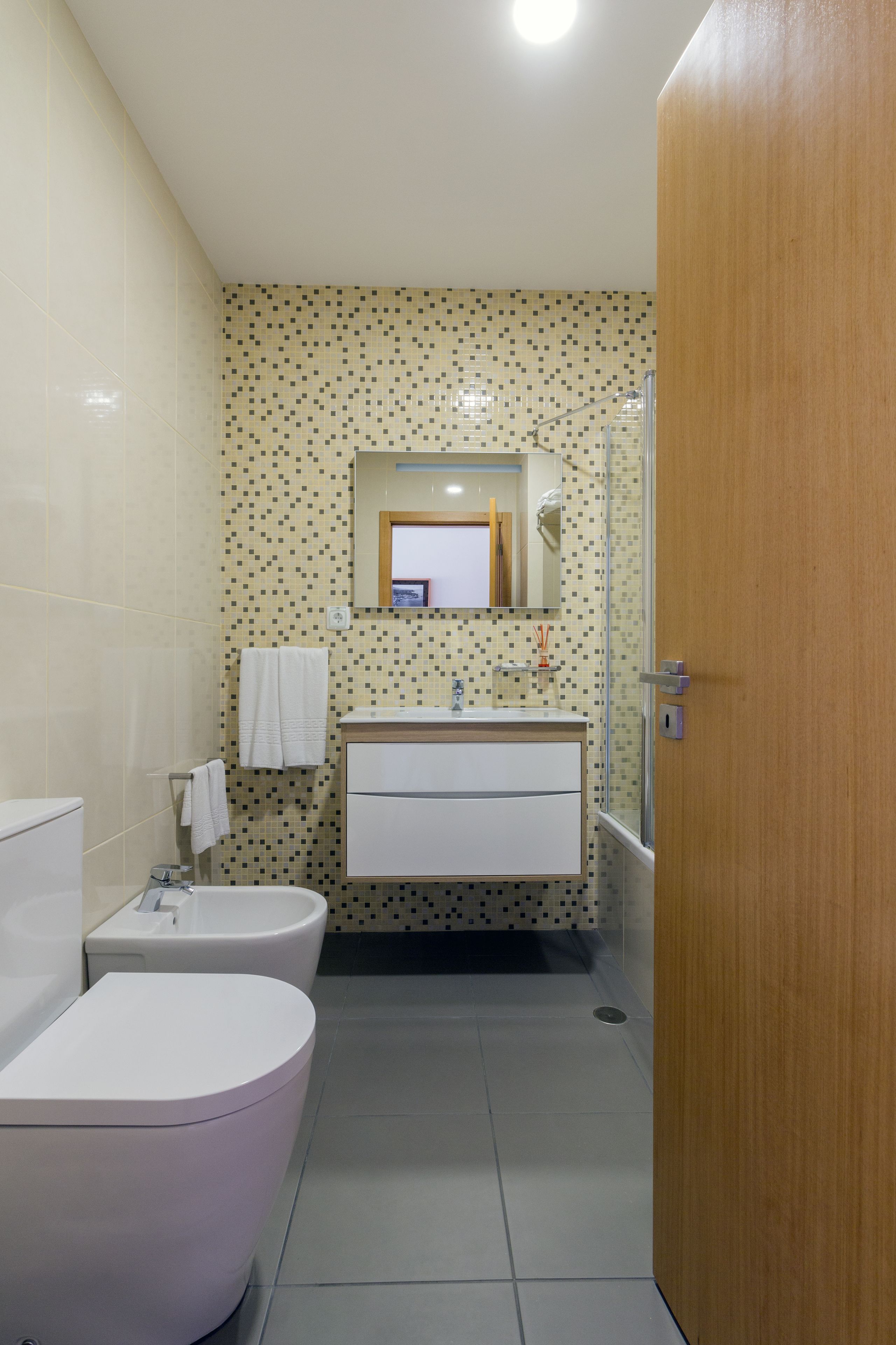 Ein Badezimmer mit Toilette, Bidet, Waschbecken und Spiegel.
