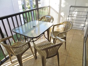 Enjoy a peaceful moment on the balcony with a glass-top table and comfortable seating for four.