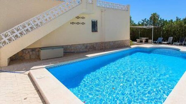 A swimming pool with a white decorative wall and a small window.