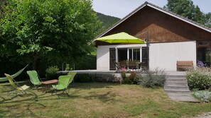 A house with a patio area, outdoor seating, and a wooden deck. - SEVRIER,Plain pied, Spacieuse Villa, jardin, 8pers (Sévrier)
