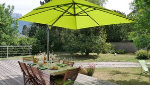 An outdoor dining area with a table set for four, a bright yellow umbrella, and a wooden deck. - SEVRIER,Plain pied, Spacieuse Villa, jardin, 8pers (Sévrier)