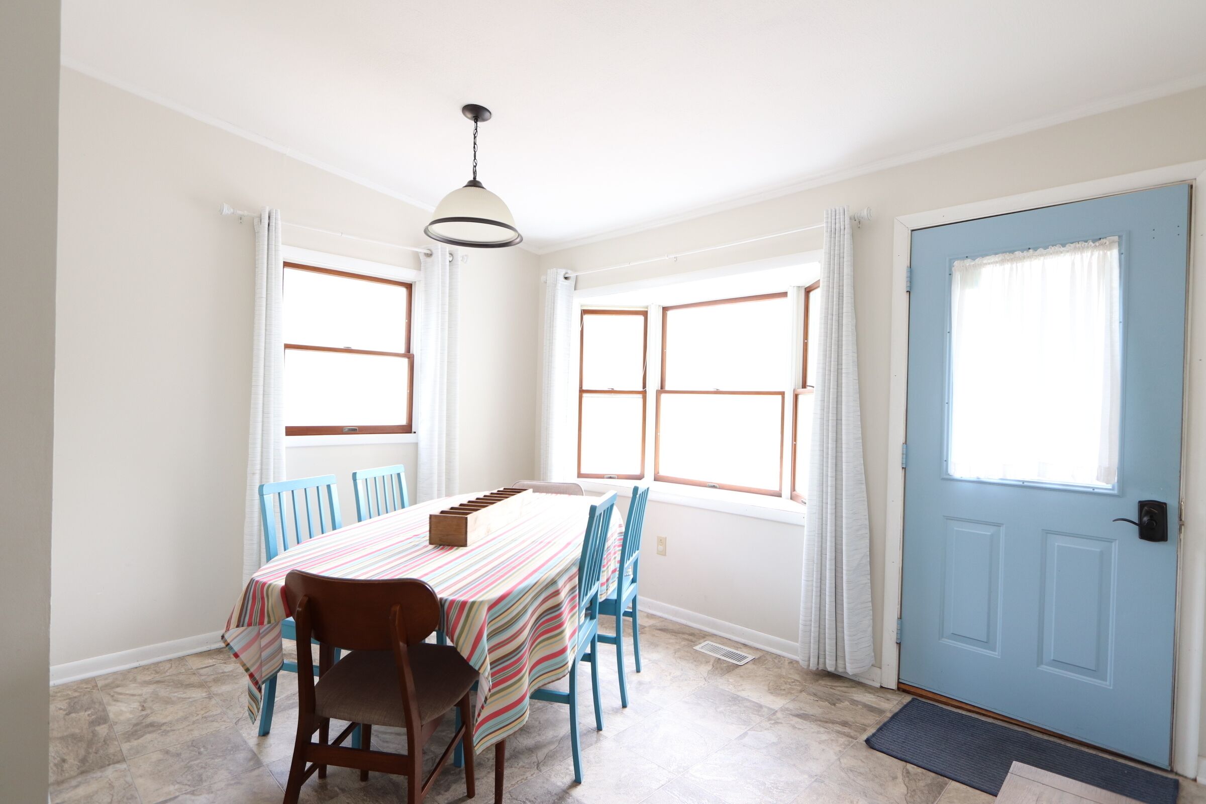 A dining area with a table set for four, blue chairs, and a striped tablecloth.