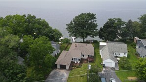 Un quartiere residenziale con case, un grande albero e una massa d'acqua sullo sfondo.
