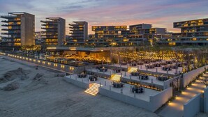 Un hôtel moderne à plusieurs étages, doté d’espaces de restauration en plein air et offrant une vue sur le front de mer.