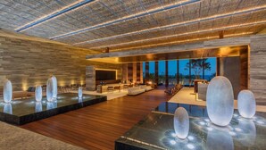 Un vaste espace intérieur doté d’un plancher en bois, d’un coin salon avec des canapés et des fauteuils, et d’une grande fenêtre donnant sur l’extérieur.