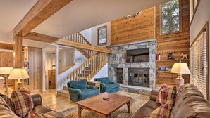 A spacious living room with a stone fireplace, wooden beams, and a staircase. - Luxe Vail Valley Retreat w/ Hot Tub! (Avon)