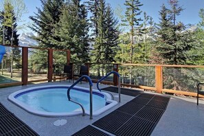 Relax in a hot tub on an outdoor deck with a serene mountain view.