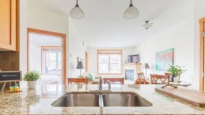 A kitchen with granite countertops, a stainless steel sink, wooden cabinets, and pendant lighting. - Mountain Paradise"at Falcon Crest Lodge (Canmore)