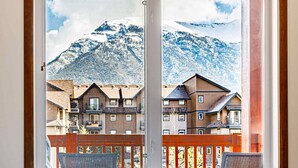 A room with a large window overlooking a snowy mountain and buildings. - Mountain Paradise"at Falcon Crest Lodge (Canmore)