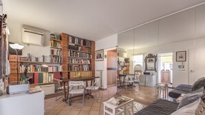 A spacious living area with a large bookshelf, a comfortable sofa, and a dining table. - COLOSSEUM a stone's throw from (Roma)