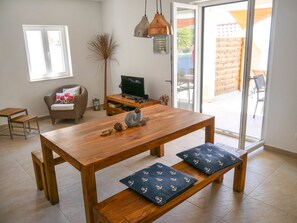 En moderne stue med et træspisebord, bænk, sofa og fjernsyn.