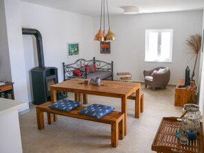 Una sala de estar acogedora con una mesa de madera, bancos, un sofá, una chimenea y un ventanal.