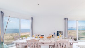 A dining area with a table set for four, overlooking a beach. - YourHouse Solmarina Son Serra (Son Serra de Marina)