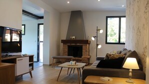 A living room with a fireplace, a television, a sofa, and a lamp. - L'Ehappée Belle - 2 to 8 people - Lake view (Maisod)