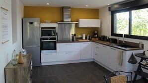 A modern kitchen with a stainless steel refrigerator, oven, and microwave. There is a window providing natural light and a view of greenery outside. - L'Ehappée Belle - 2 to 8 people - Lake view (Maisod)