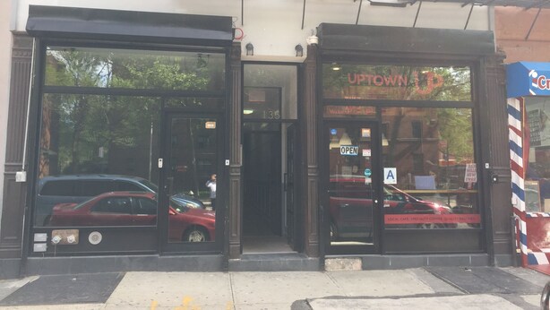 Un escaparate con amplios ventanales de vidrio, un balcón de metal y un letrero que dice "UPTOWN".