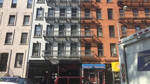 Un edificio de varios pisos con escaleras de emergencia, una barbería y vehículos estacionados.