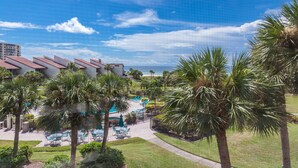 A resort with a pool area, palm trees, and a view of the ocean.