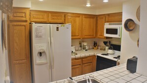 A kitchen with wooden cabinets, a refrigerator, a microwave, and a coffee maker.