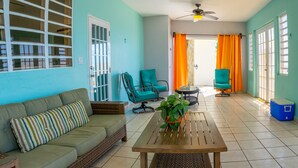A room with a green sofa, two teal chairs, a wooden table, and a ceiling fan. - Villa Ada - Oceanfront - 6 guests - pet friendly - at Stella, Rincón (Rincon)