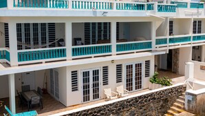 A multi-story building with balconies, a dining area, and a stone retaining wall. - Villa Ada - Oceanfront - 6 guests - pet friendly - at Stella, Rincón (Rincon)