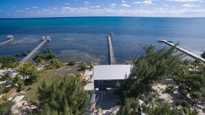 A coastal property with a dock extending into the sea, a small building, and surrounding greenery. - Box House Boca Ciega - Unique Beachfront Container Home (San Pedro)