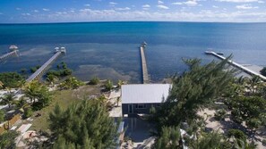 A coastal property with a dock extending into the sea, a small building, and surrounding greenery. - Box House Boca Ciega - Unique Beachfront Container Home (San Pedro)