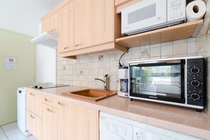 Een koelkast, een magnetron, een vaatwasser, kookgerei, borden en bestek