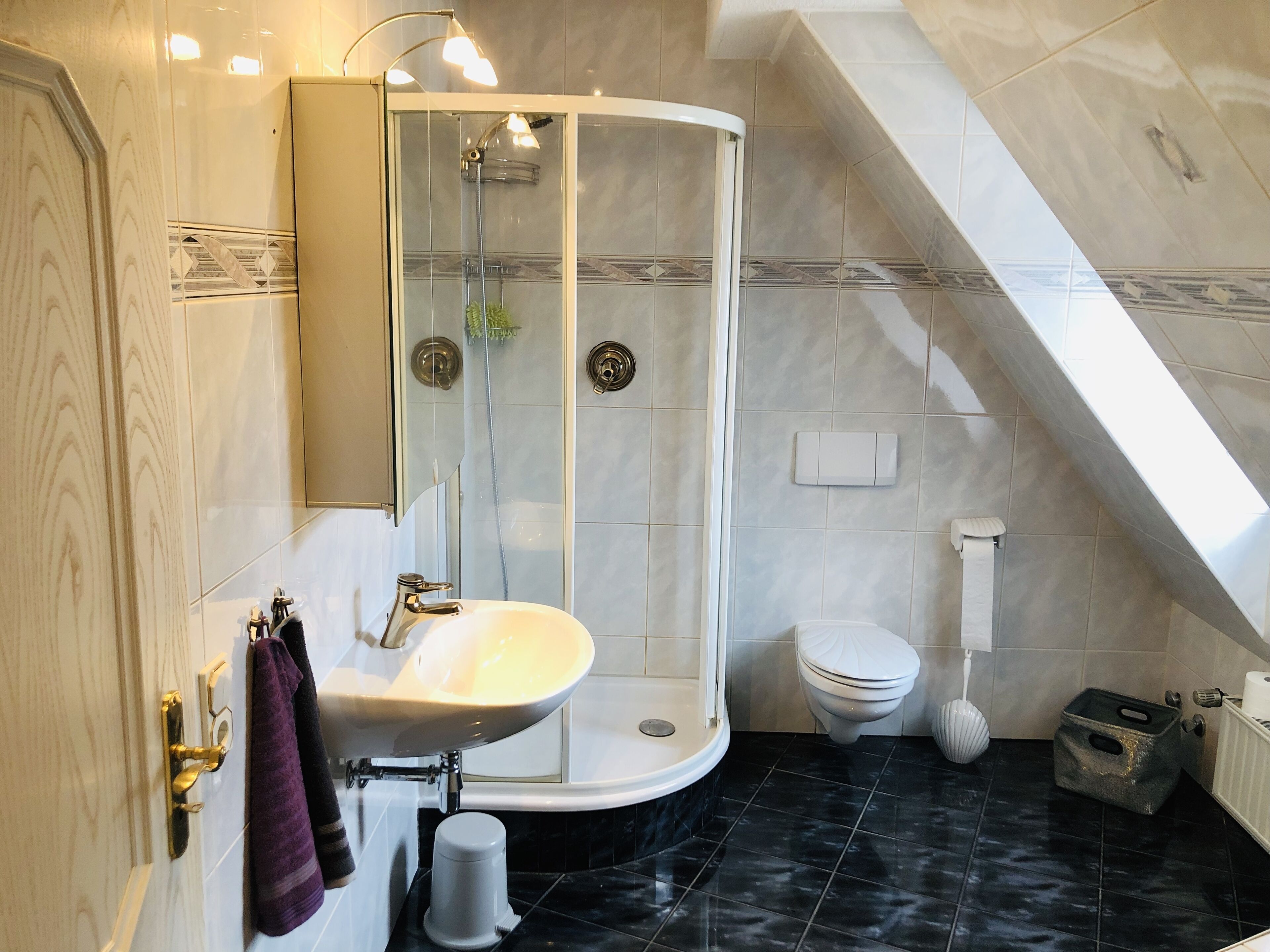 Une salle de bain moderne avec une douche à forme arrondie, un lavabo blanc et des toilettes.