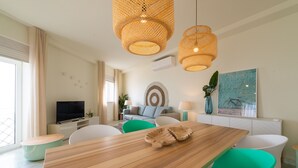 Una sala de estar moderna con una mesa de comedor de madera, sillas verdes, un televisor y un cuadro en la pared.