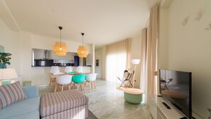 Una sala de estar moderna con sofá, reposapiés, televisor y comedor con sillas y una mesa.