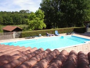Ein Schwimmbecken mit Liegestühlen und ein kleines Gebäude im Hintergrund.