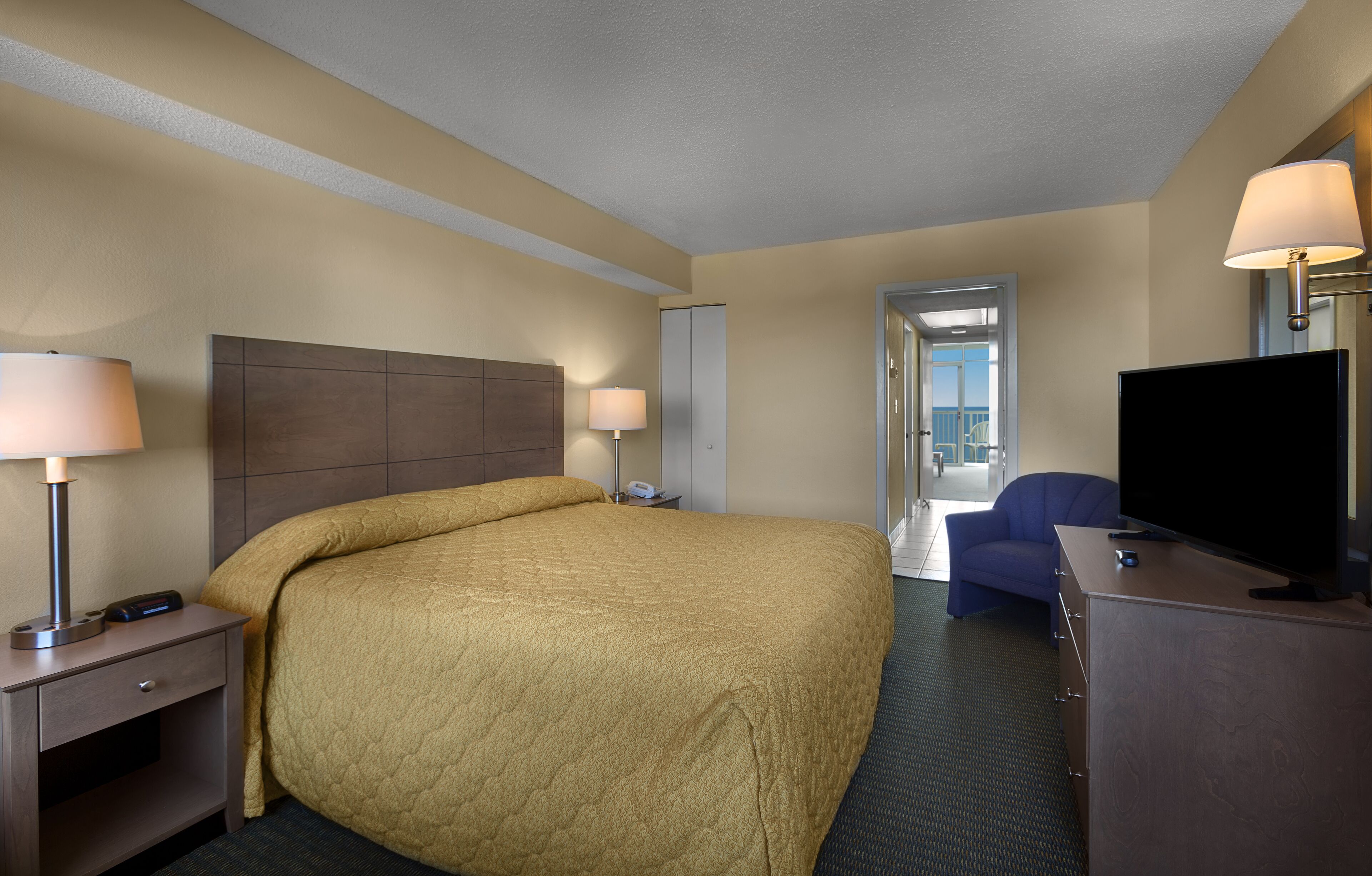 A hotel room with a large bed, bedside lamps, a desk with a flat-screen TV, and a chair.