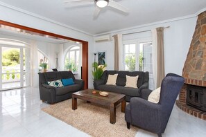 A modern living room with a fireplace, two sofas, a coffee table, and a large window with curtains.
