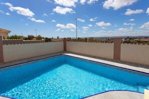 Ein rechteckiger Swimmingpool mit klarem, blauem Wasser, umgeben von einer niedrigen Mauer mit dekorativem Muster.