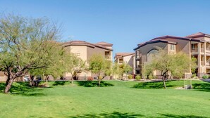 A residential building with multiple balconies, a well-maintained lawn, and trees. - Resort Style Vacation Condo (Mesa)