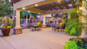 An outdoor patio area with tables and chairs, surrounded by potted plants and a covered structure. - Resort Style Vacation Condo (Mesa)