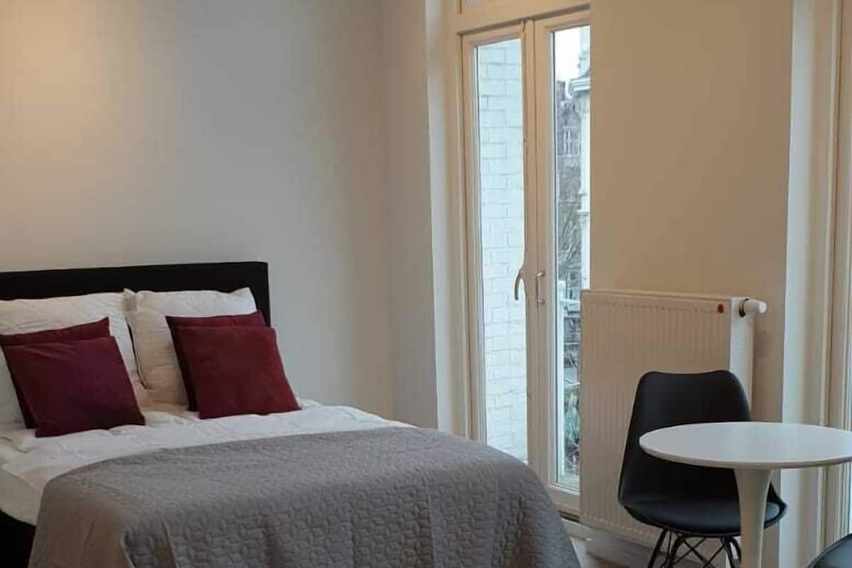 Une chambre d’hôtel moderne avec un lit, une table ronde et deux chaises.