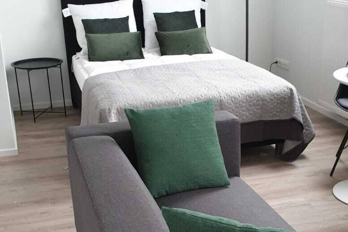 Une chambre à coucher moderne avec un lit, un canapé gris et une petite table.