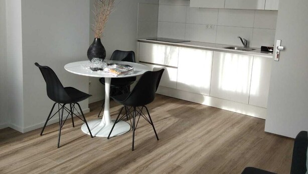 Una cocina moderna con armarios blancos, horno integrado y pileta de acero inoxidable.